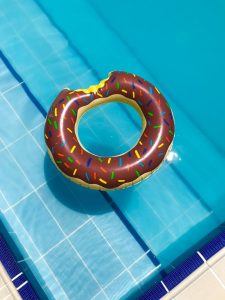 Home A vibrant donut-shaped float rests on a clear swimming pool. Perfect for summer vibes.