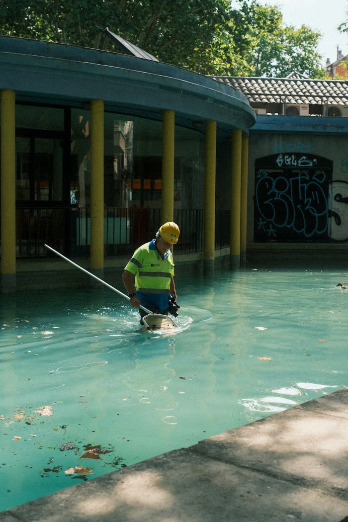 services-bg A pool maintenance worker wearing safety gear cleans an outdoor pool in Barcelona, Spain.