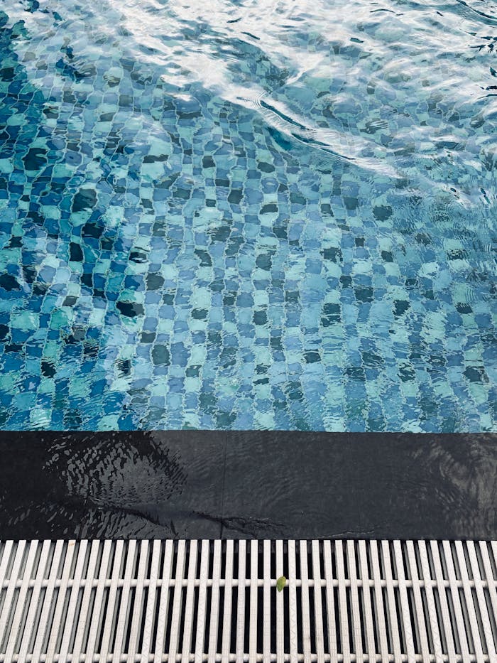 services-02 A close-up view of clean blue swimming pool water with ripples and a tiled floor.