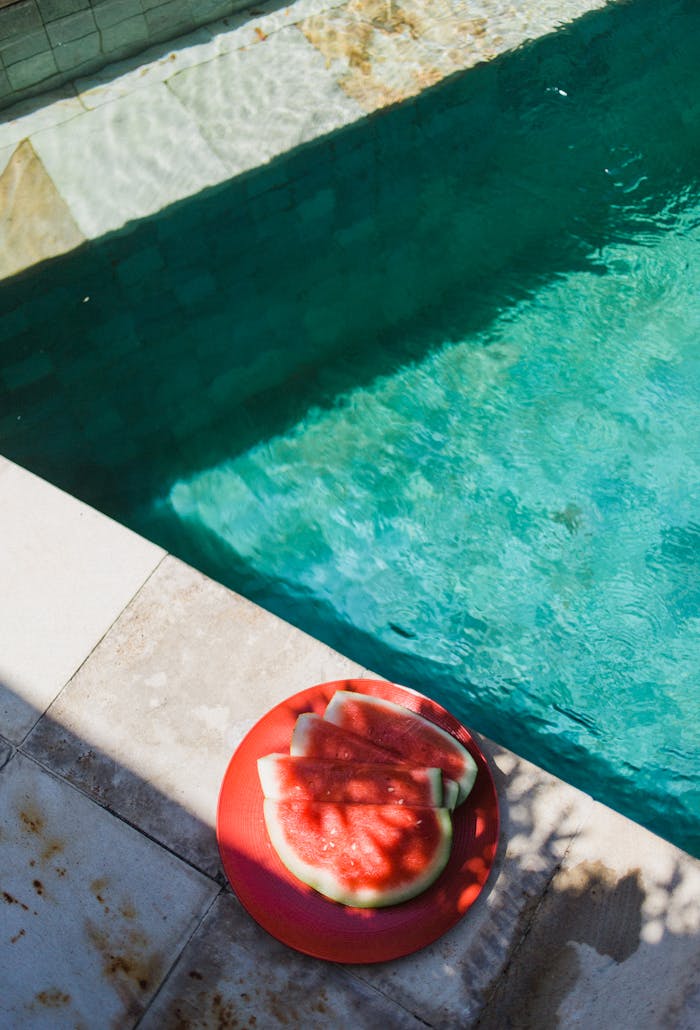 Crafting Captivating Headlines: Your awesome post title goes here From above of small red slices of watermelon on round plate next to turquoise swimming pool in sunlight