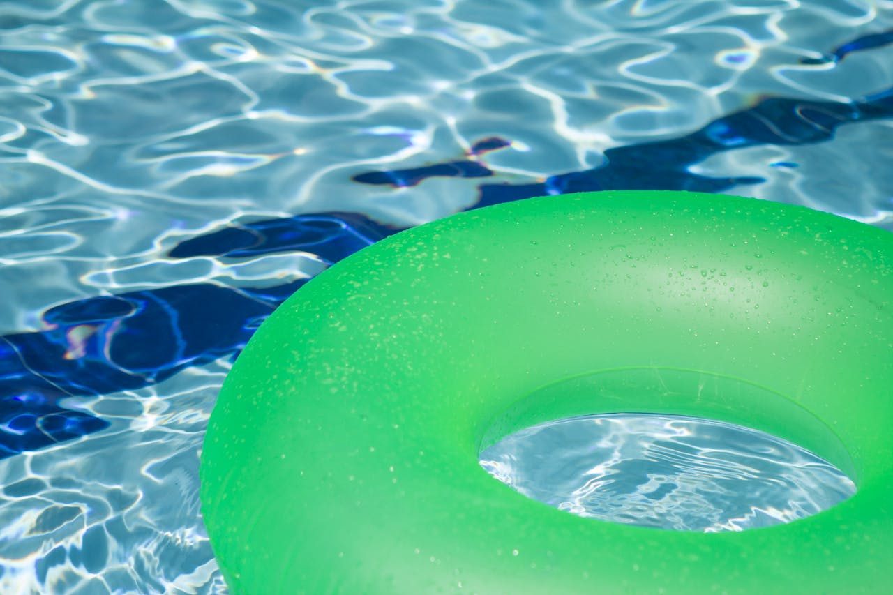 services-04 A vibrant green inflatable swim ring floating in a refreshing blue swimming pool.
